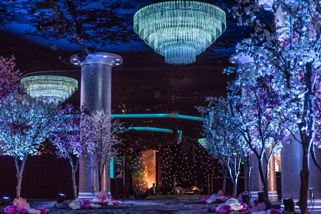 Illuminated purple trees and a chandelier at a special event.